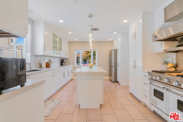 kitchen with wall chimney exhaust hood, sink, hanging light fixtures, a kitchen island, and white cabinets