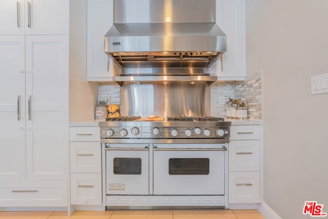 kitchen featuring range with two ovens, exhaust hood, white cabinets, and decorative backsplash