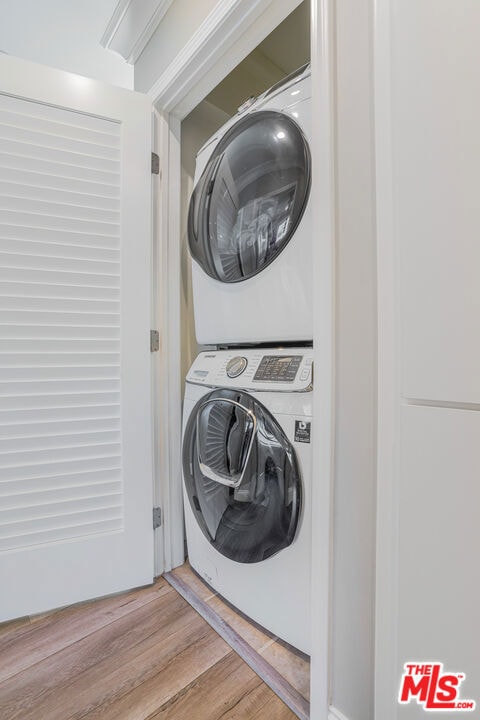 laundry room featuring light wood-type flooring and stacked washer / dryer