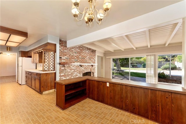 kitchen featuring pendant lighting, a brick fireplace, beamed ceiling, and white refrigerator