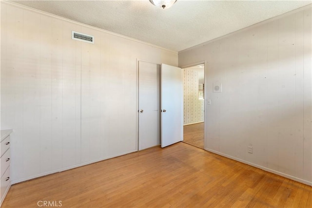 unfurnished bedroom with a textured ceiling, light hardwood / wood-style floors, and a closet