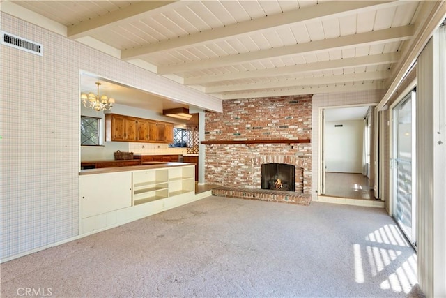 unfurnished living room with a notable chandelier, a brick fireplace, beam ceiling, and light colored carpet