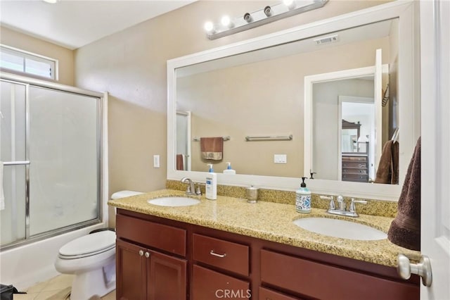 full bathroom with tile patterned flooring, vanity, combined bath / shower with glass door, and toilet