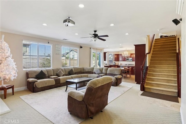 carpeted living room with ceiling fan with notable chandelier