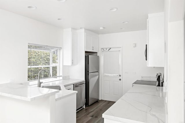 kitchen featuring sink, light hardwood / wood-style flooring, white cabinetry, stainless steel appliances, and kitchen peninsula