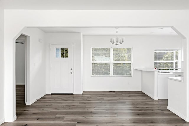 interior space featuring a healthy amount of sunlight, a notable chandelier, and dark hardwood / wood-style flooring