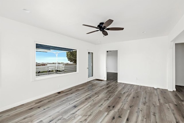 empty room with visible vents, wood finished floors, baseboards, and ceiling fan