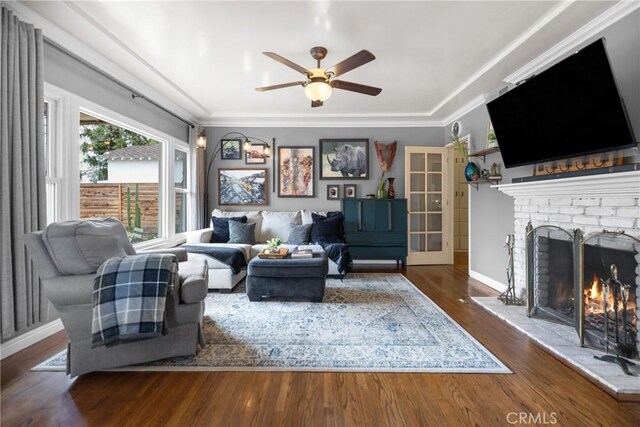 living room featuring ceiling fan, ornamental molding, dark hardwood / wood-style floors, and a fireplace