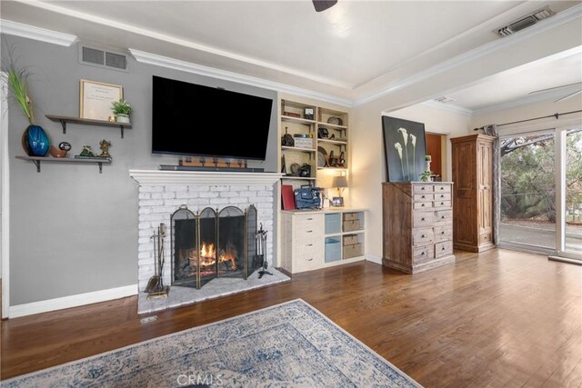 living room featuring crown molding, ceiling fan, a fireplace, and dark hardwood / wood-style flooring