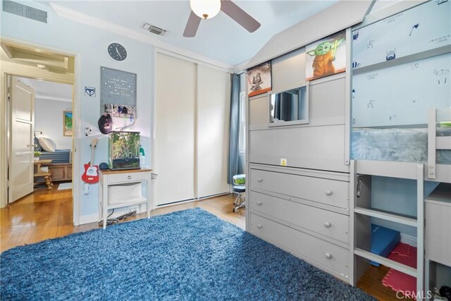 bedroom featuring crown molding, lofted ceiling, light wood-type flooring, and a closet