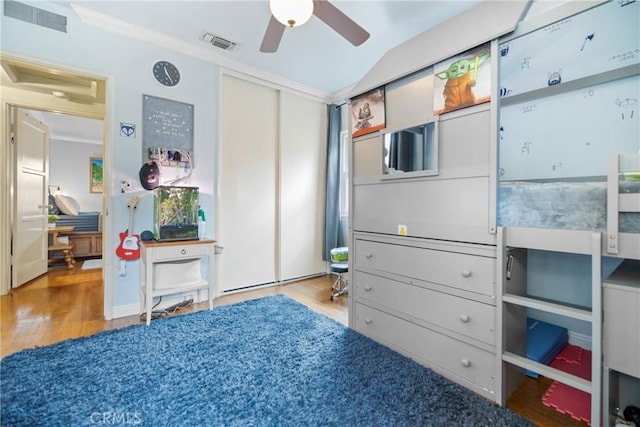 bedroom with vaulted ceiling, a closet, crown molding, and light hardwood / wood-style flooring