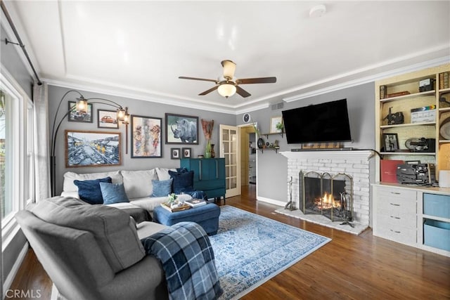 living room with ornamental molding, dark hardwood / wood-style floors, ceiling fan, and a fireplace