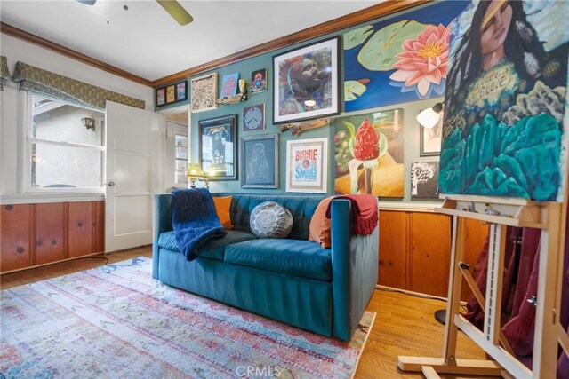 sitting room featuring crown molding, wood-type flooring, and ceiling fan