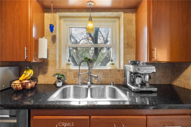 kitchen featuring tasteful backsplash, hanging light fixtures, sink, and dark stone counters