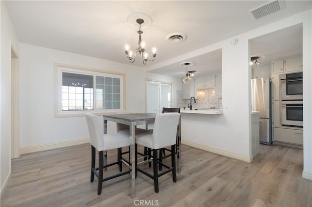 56766 Golden Bee Dr, Yucca Valley, CA 92284 - dining room with a chandelier, light wood finished floors, and baseboards
