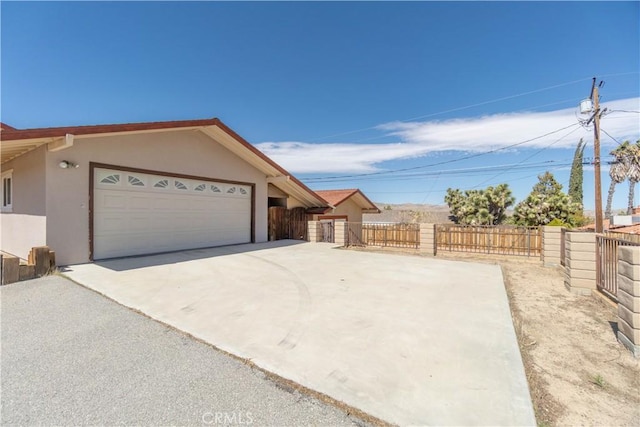 56766 Golden Bee Dr, Yucca Valley, CA 92284 - view of front facade featuring stucco siding, driveway, a garage, and fence