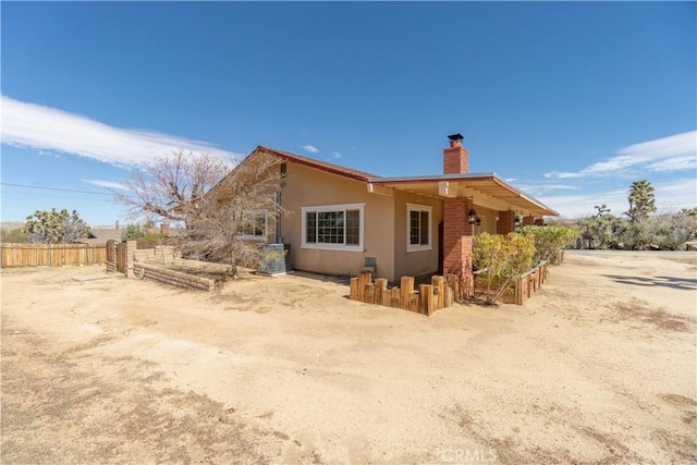 56766 Golden Bee Dr, Yucca Valley, CA 92284 - back of house with a chimney, fence, and stucco siding
