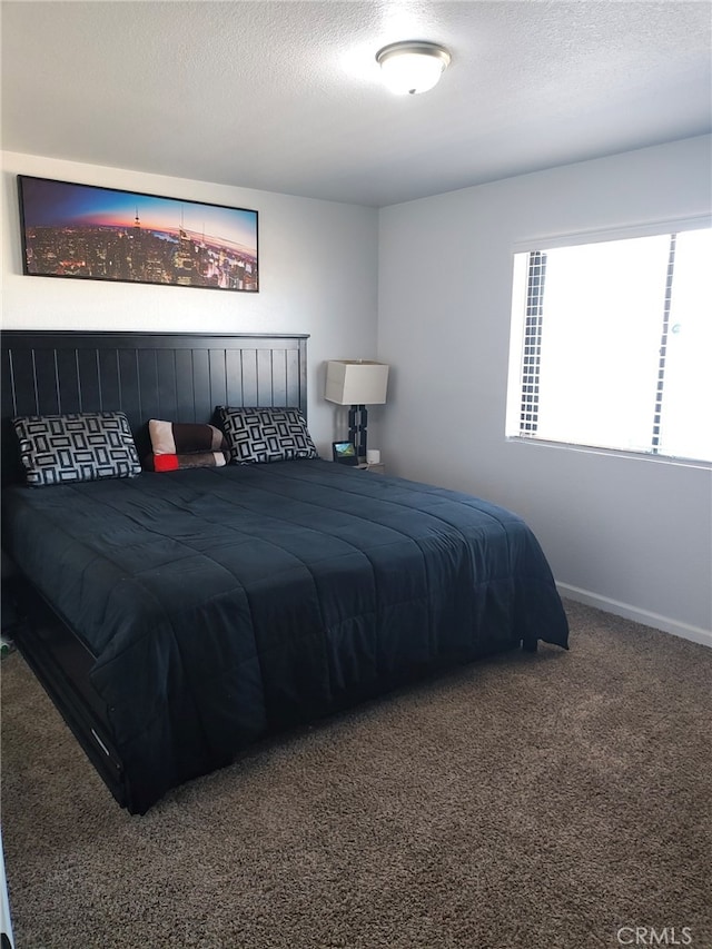 bedroom with carpet flooring, a textured ceiling, and baseboards