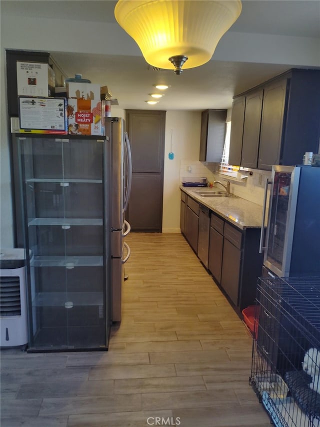 kitchen with dark brown cabinetry, light wood-style flooring, appliances with stainless steel finishes, and a sink