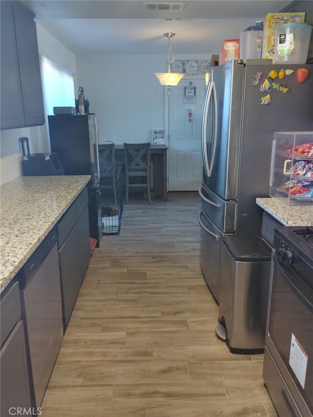 kitchen featuring stainless steel appliances, light wood-type flooring, decorative light fixtures, and light stone countertops