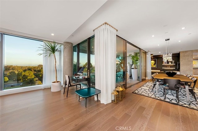 interior space with a chandelier, recessed lighting, a wall of windows, and wood finished floors