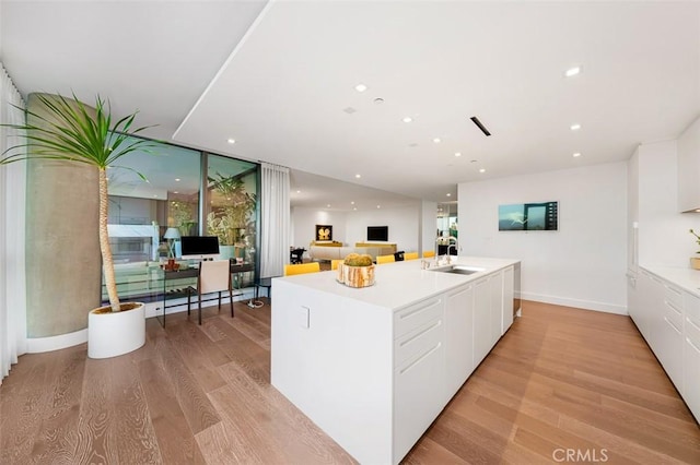 kitchen featuring white cabinetry, floor to ceiling windows, light wood finished floors, and a sink