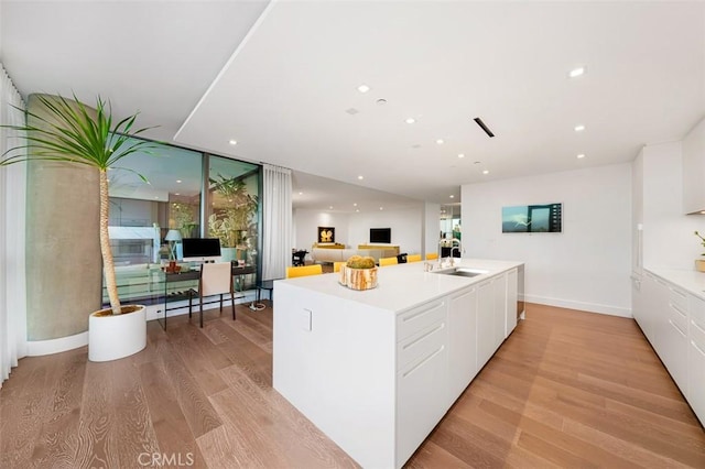 kitchen featuring white cabinets, recessed lighting, light wood-style flooring, and a sink