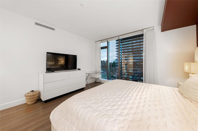 bedroom featuring access to exterior, visible vents, baseboards, floor to ceiling windows, and wood finished floors