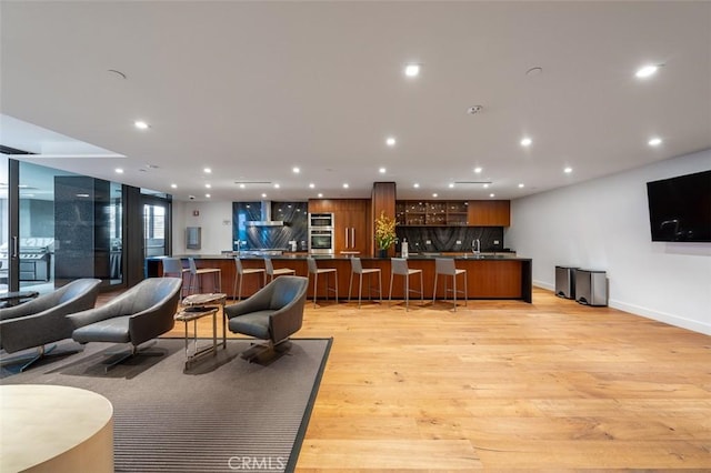 interior space with wet bar, recessed lighting, light wood-type flooring, and baseboards