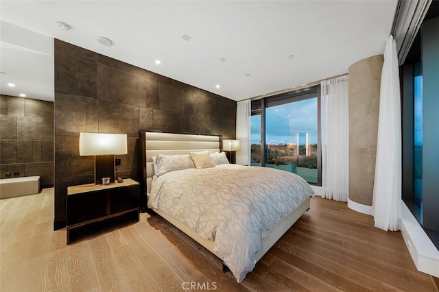 bedroom with recessed lighting, tile walls, wood finished floors, and access to outside