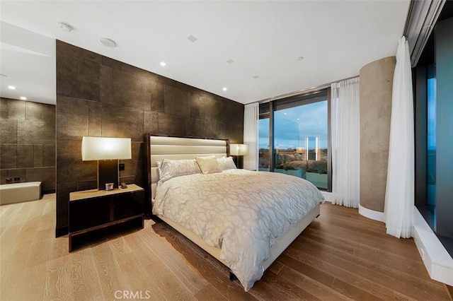 bedroom featuring tile walls, wood finished floors, and access to outside