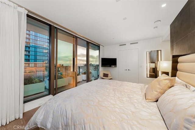 bedroom with access to exterior, a wall of windows, and wood-type flooring