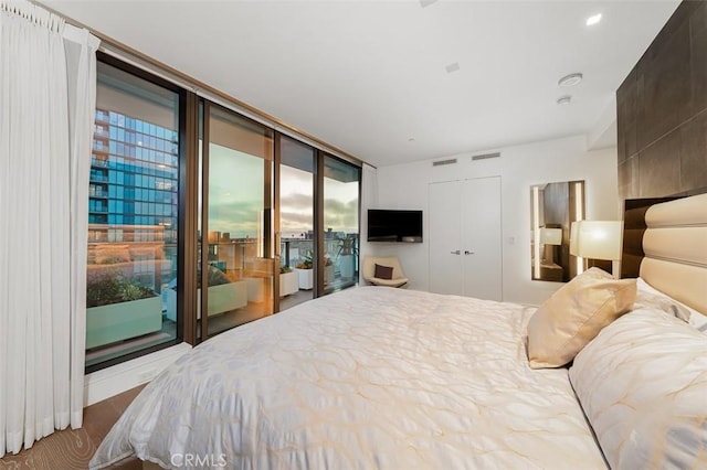 bedroom with visible vents, wood finished floors, a closet, and access to exterior