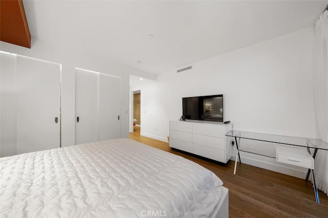 bedroom with wood finished floors, visible vents, and baseboards