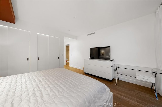 bedroom featuring wood finished floors, visible vents, and baseboards
