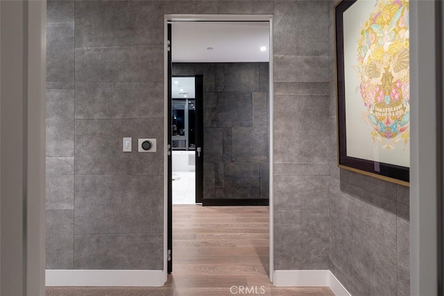 hallway with hardwood / wood-style flooring and tile walls