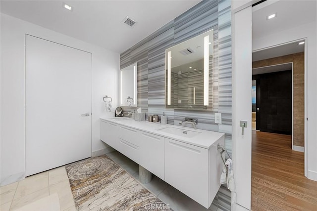 bathroom with tile walls, double vanity, visible vents, and a sink