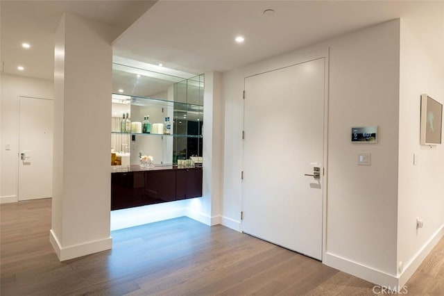 entryway with recessed lighting, baseboards, wood finished floors, and a dry bar