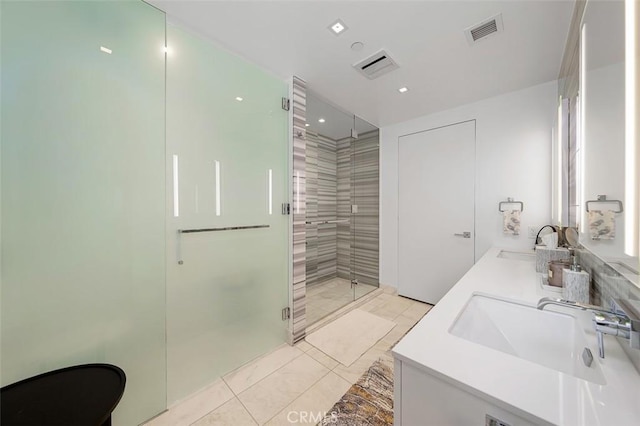 full bath with double vanity, visible vents, a shower stall, and a sink