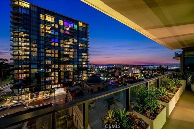 balcony at dusk featuring a city view