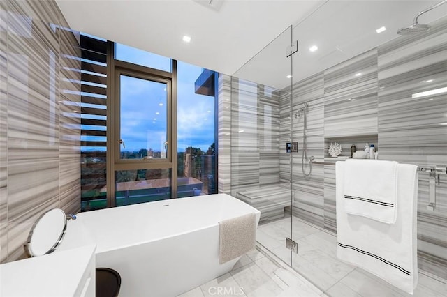 bathroom featuring plus walk in shower and tile walls