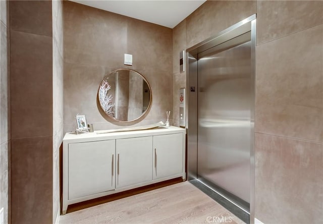 2855 5th Ave Unit 703, San Diego, CA 92103 - bathroom featuring wood finished floors, vanity, elevator, and tile walls