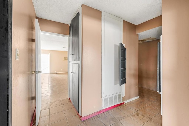 corridor with a textured ceiling and light tile patterned floors