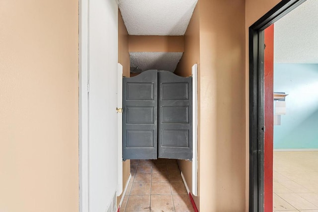 hallway featuring light tile patterned flooring and a textured ceiling