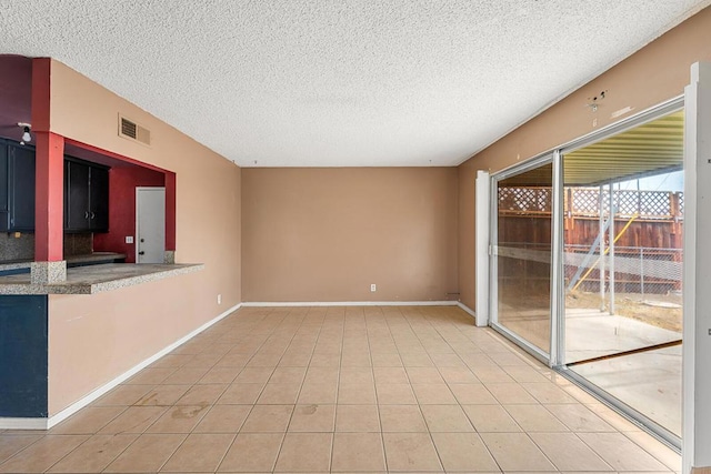 tiled empty room with a textured ceiling