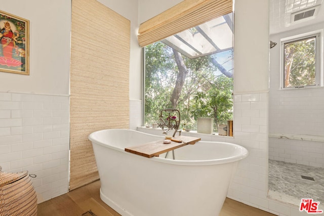 bathroom featuring a bathing tub, wood-type flooring, and tile walls