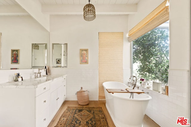 bathroom with a tub to relax in, beam ceiling, tile walls, and vanity