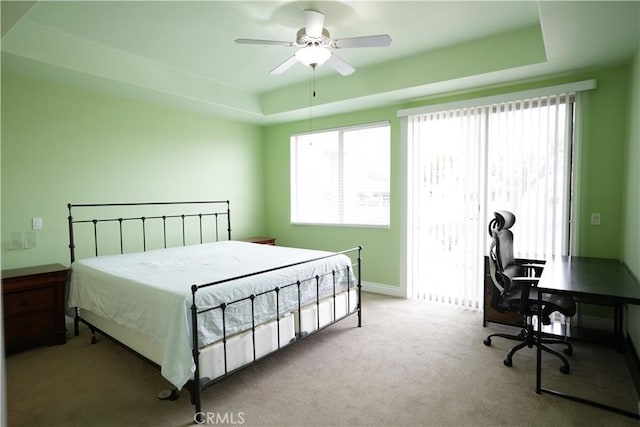 bedroom with light colored carpet, ceiling fan, and a tray ceiling