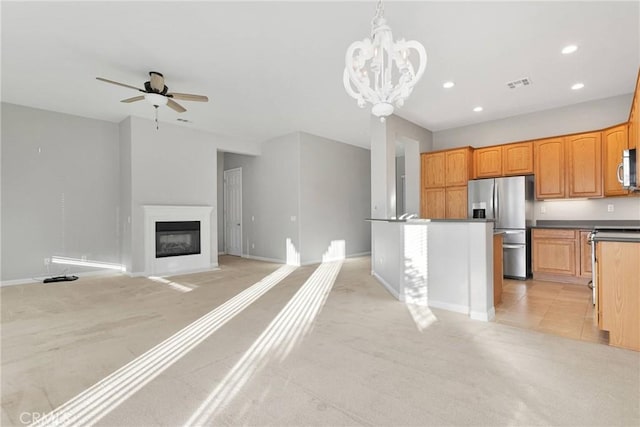 kitchen with a center island, appliances with stainless steel finishes, pendant lighting, light colored carpet, and ceiling fan with notable chandelier