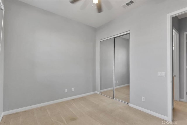 unfurnished bedroom with ceiling fan, light colored carpet, and a closet